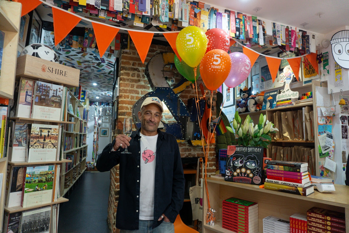 Book shop owner holding a glass celebrating 5 years of business